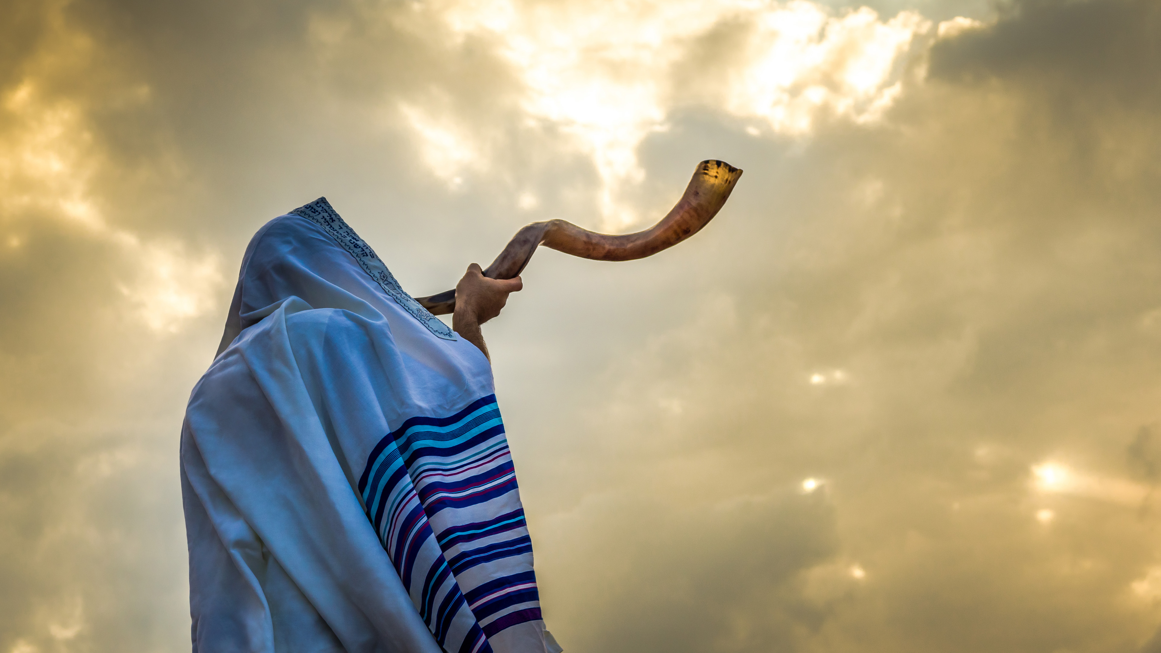 Jewish person in a tallit prayer shawl against dramatic sky