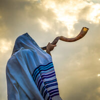 Jewish person in a tallit prayer shawl against dramatic sky